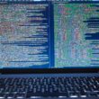 Laptop displaying source code with dual screens for software development.